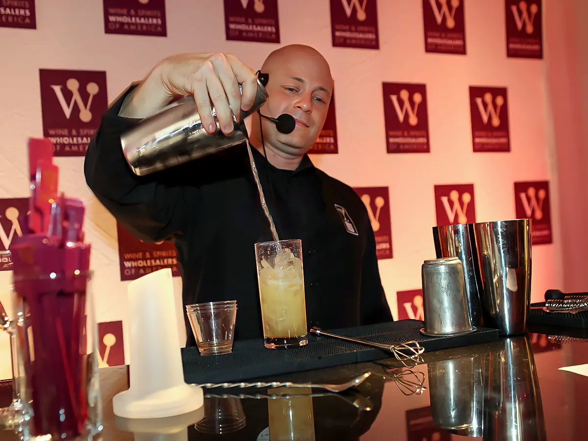 A Man Pouring a Drink After Mixing into a Glass