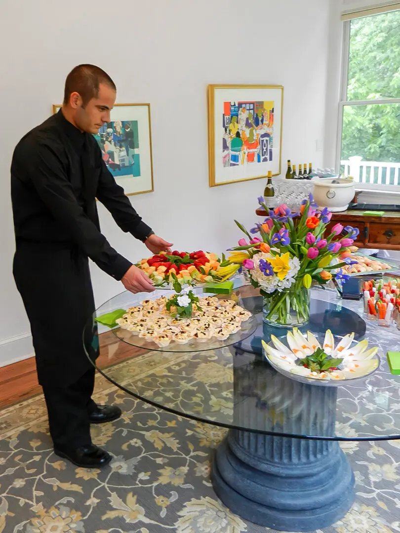 A Man Arranging Flowers on a Glass Table